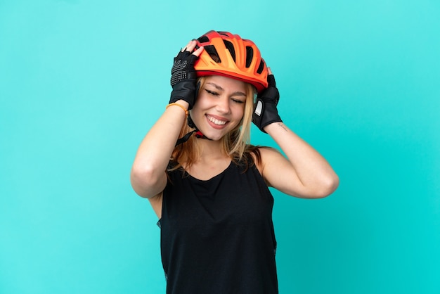 Ragazza giovane ciclista su sfondo blu isolato ridendo