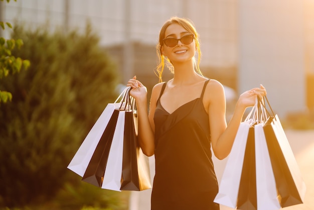 Ragazza giovane con borse della spesa colorate in giro per la città dopo lo shopping.