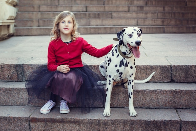 Ragazza giovane con i suoi cani dalmata in un parco di primavera.