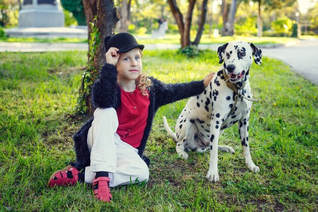 Ragazza giovane con i suoi cani dalmata in un parco di primavera.