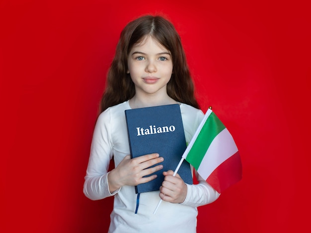 Ragazza giovane con un libro di testo di lingua italiana e una bandiera, scuola di lingue che impara l'italiano