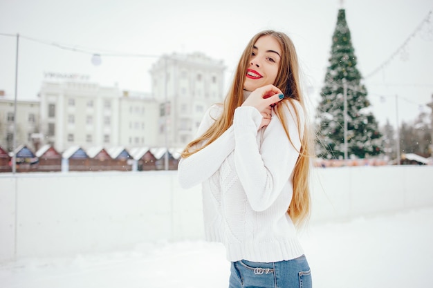 Ragazza giovane con un maglione bianco in piedi in un parco invernale