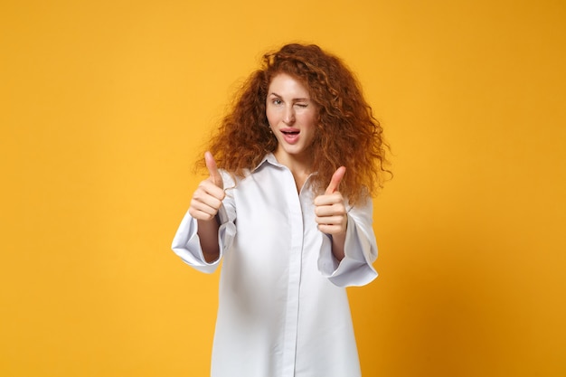 Ragazza giovane donna dai capelli rossi in camicia bianca casual in posa isolata sul muro giallo arancione