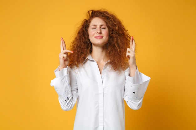 Ragazza giovane donna dai capelli rossi in camicia in posa isolata sul muro giallo arancione