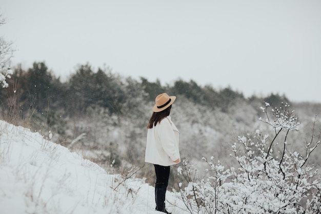 Ragazza giovane guardando un paesaggio fantastico in montagna innevata a nevicata.