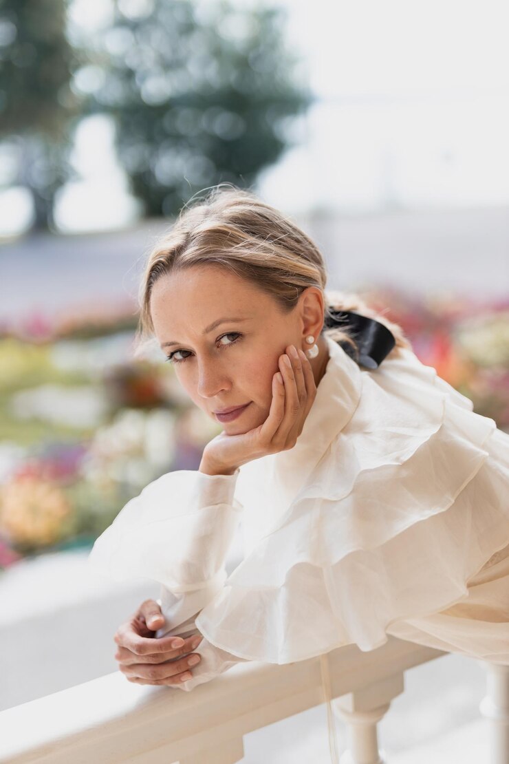 Ragazza giovane in camicia bianca e gonna nera che guarda fuori dalla finestra e pensa al futuro