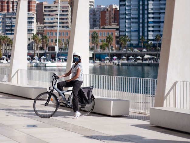 Ragazza giovane in sella ad una bicicletta attraverso il porto