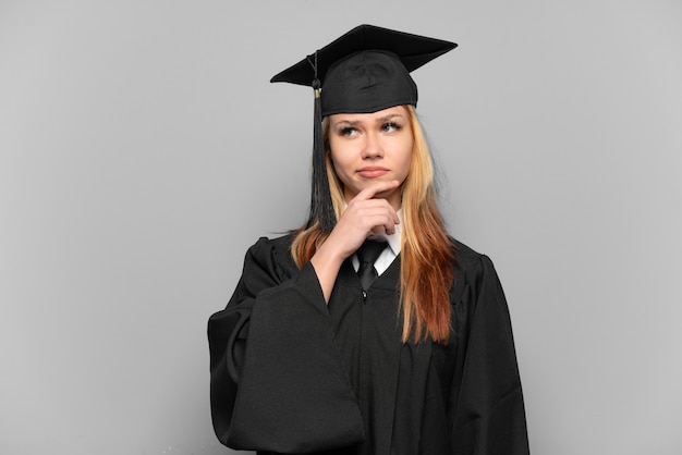 Ragazza giovane laureato universitario sopra priorità bassa isolata che ha dubbi