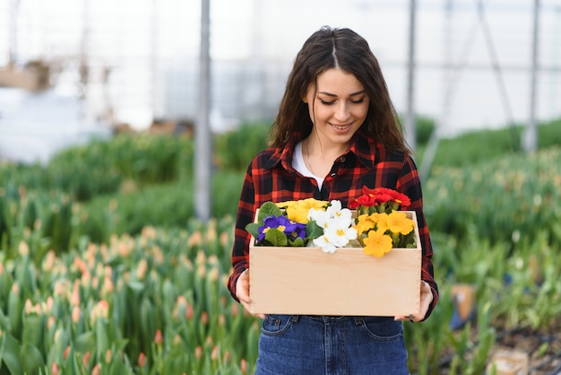 Ragazza giovane, operaio con fiori in serra