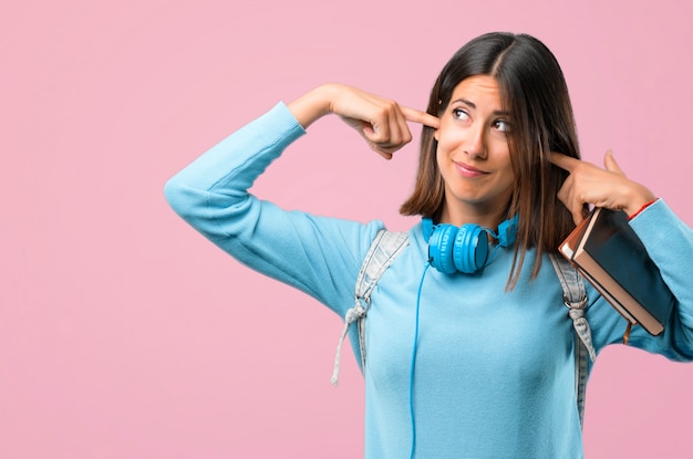 Ragazza giovane studente con maglione blu e cuffie che coprono entrambe le orecchie. di nuovo a scuola