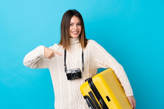 Ragazza giovane viaggiatore con la valigia sul muro blu