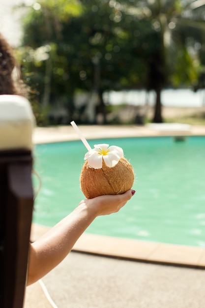 ragazza gode di relax vicino alla piscina, con un cocktail in una noce di cocco.