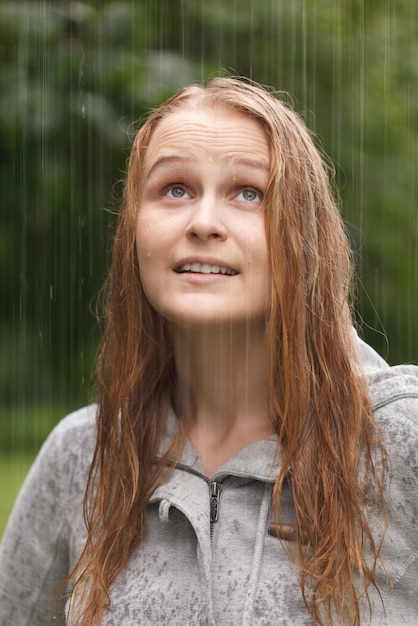 Ragazza godendo la pioggia nel parco.