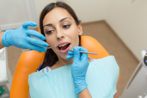 Ragazza graziosa che ha controllo di bocca in ospedale dal dentista professionista.