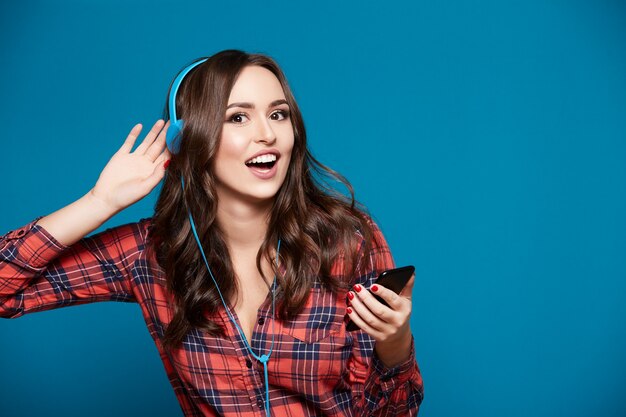 Ragazza graziosa che posa alla parete blu