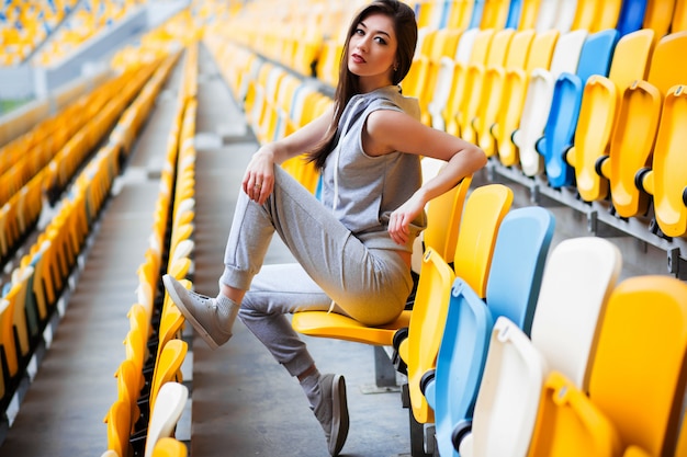 Ragazza graziosa che si siede allo stadio della scuola