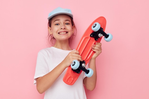 Ragazza graziosa con uno skateboard in mano infanzia inalterata