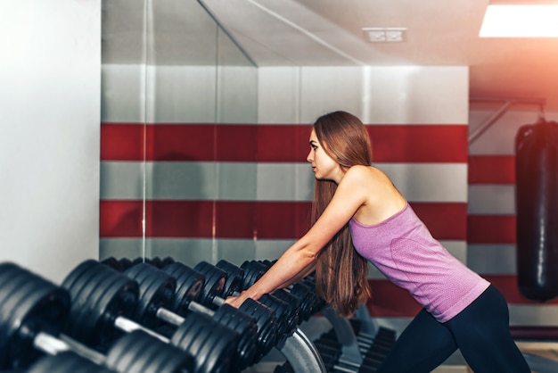 Ragazza graziosa dei capelli lunghi che si prepara in palestra