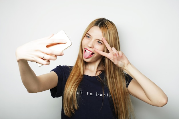 Ragazza graziosa dei pantaloni a vita bassa che prende selfie. Giovane e felice.