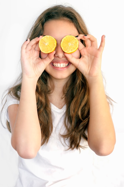 Ragazza graziosa dell&#39;adolescente che la copre occhi di limoni tagliati. Occhiali da sole al limone