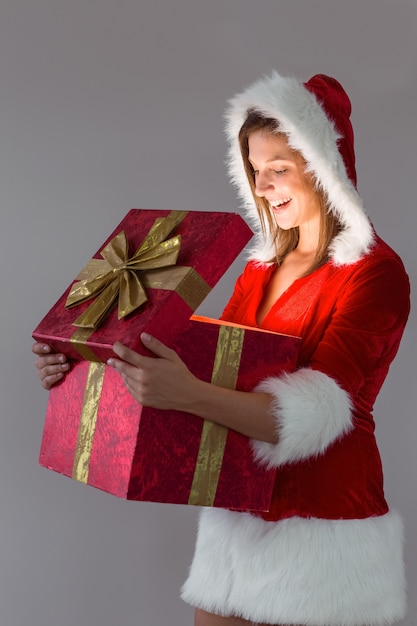 Ragazza graziosa della Santa che apre un regalo