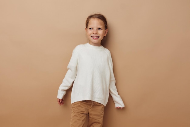 Ragazza graziosa in maglione bianco che posa lo stile di vita dei gesti della mano inalterato