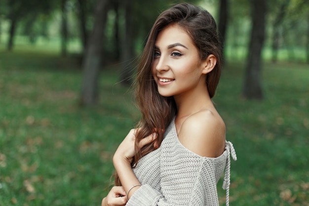 Ragazza graziosa in un maglione grigio nel parco