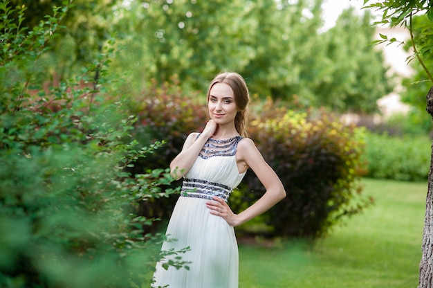 Ragazza graziosa in un vestito bianco, che cammina nel parco.