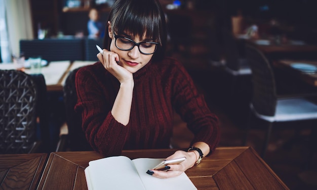 ragazza hipster che legge un messaggio di testo utilizzando la nuova applicazione per comunicare sul telefono cellulare