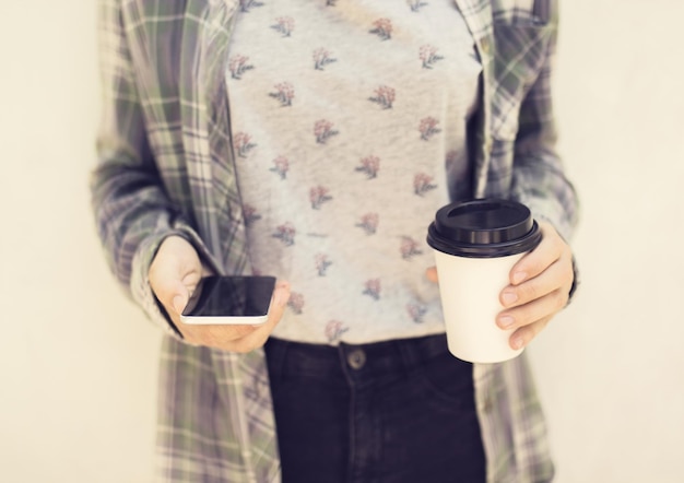 Ragazza hipster con cellulare e tazza di caffè