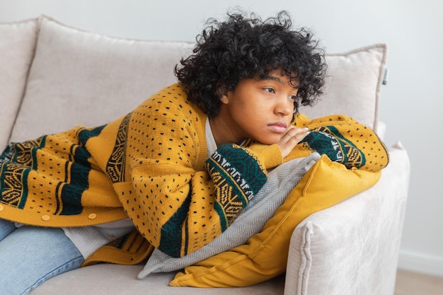 Ragazza immotivata pensosa pensosa triste dell'afroamericano che si siede sul sofà a casa giovane africa dell'interno