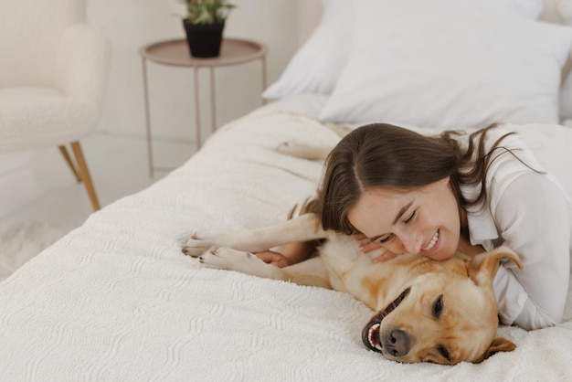 Ragazza in abiti bianchi con cane labrador che gioca a casa