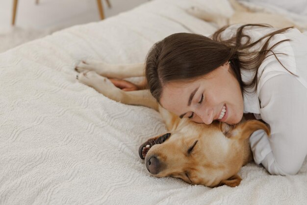 Ragazza in abiti bianchi con cane labrador che gioca a casa