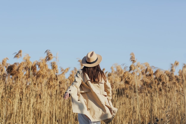 ragazza in abiti eleganti gira nel campo con le canne