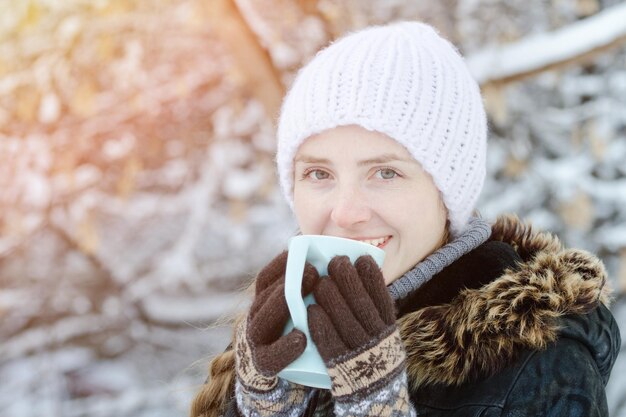 Ragazza in abiti invernali bere il tè da una tazza Primo piano vista laterale