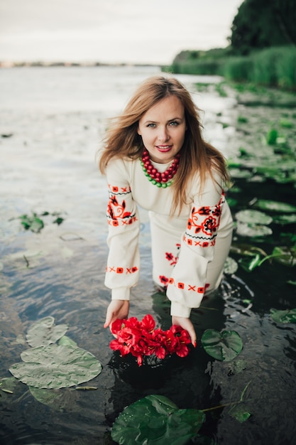 ragazza in abiti tradizionali ucraini mettendo corona di fiori in acqua