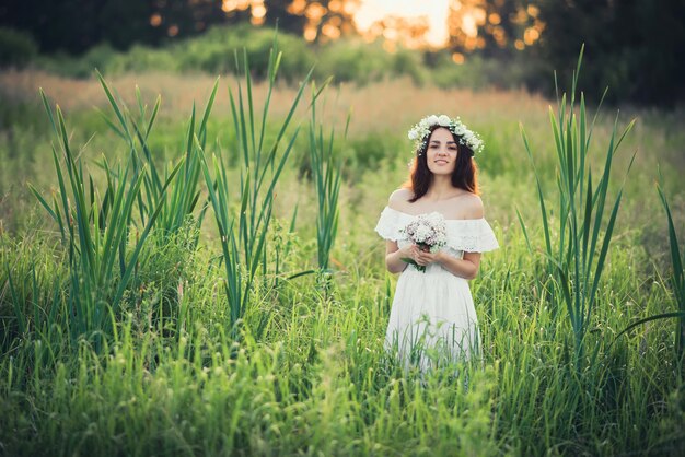 Ragazza in abito bianco con una corona e un mazzo di fiori sorridenti