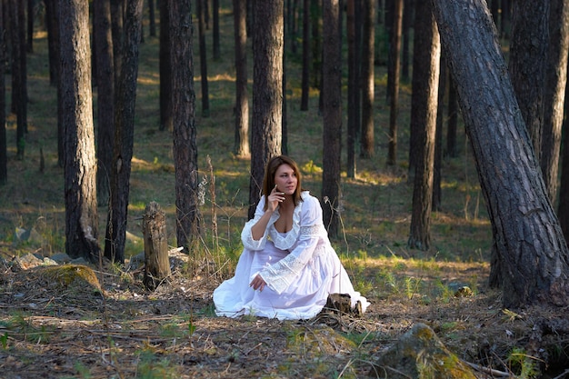 Ragazza in abito bianco nella foresta al tramonto