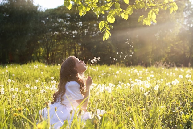 Ragazza in abito bianco soffia soffione