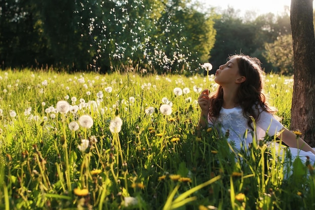 Ragazza in abito bianco soffia soffione