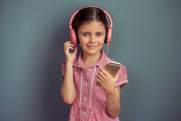 Ragazza in abito carino e cuffie sta ascoltando musica.