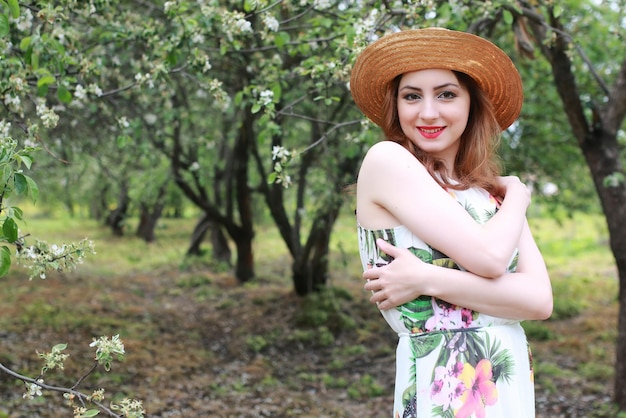 Ragazza in abito e cappello di paglia nel parco