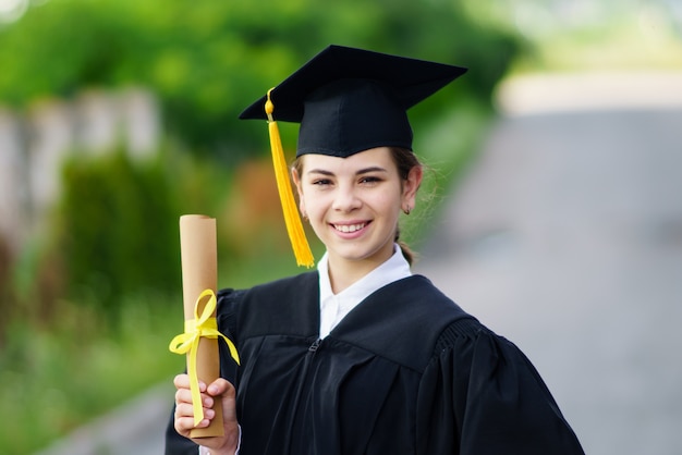 Ragazza in abito e cappuccio in possesso di un diploma