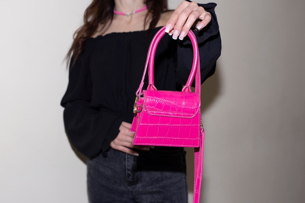 Ragazza in abito nero con una bellissima borsetta rosa in mano