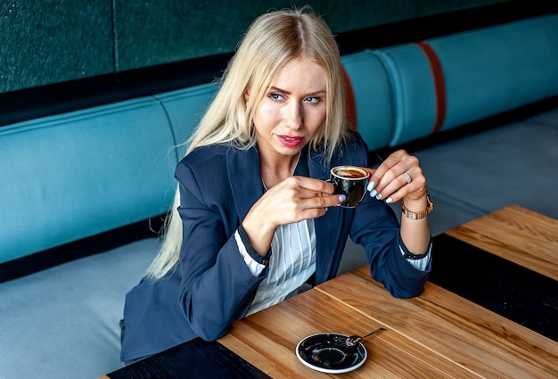 ragazza in abito rigoroso in un bar a bere il caffè