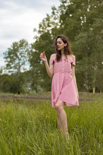 Ragazza in abito rosso sulla natura in estate Ritratto di una bella ragazza in estate nella foresta