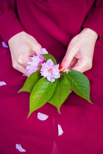 Ragazza in abito rosso tenendo sakura nelle mani