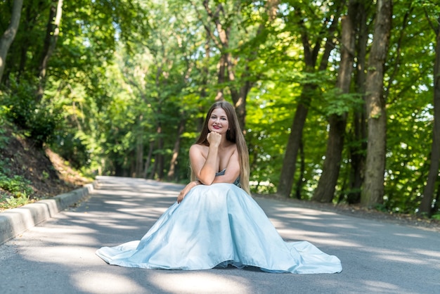 Ragazza in abito sulla strada estiva tra gli alberi