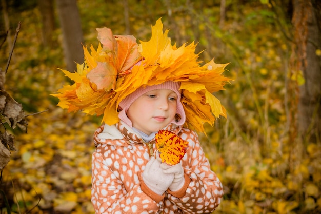 ragazza in autunno parco dorato con una corona di foglie.