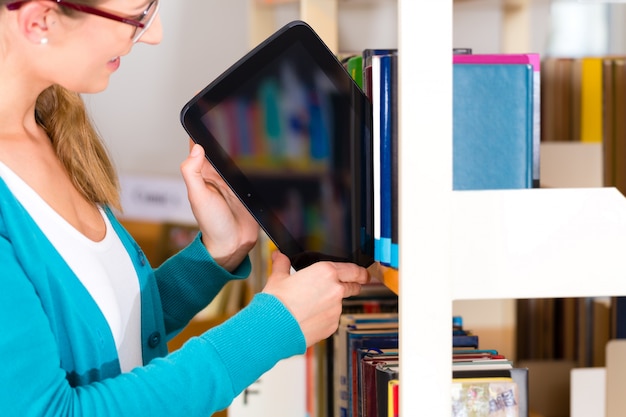 Ragazza in biblioteca con e-book o tablet computer